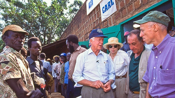 President Carter stands with people outside a building with a sign that reads CARE