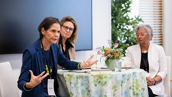 three women seated at table speaking to audience