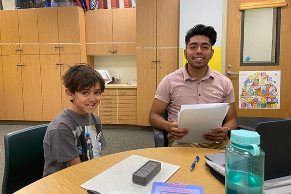 Student and adult sitting in a classroom.