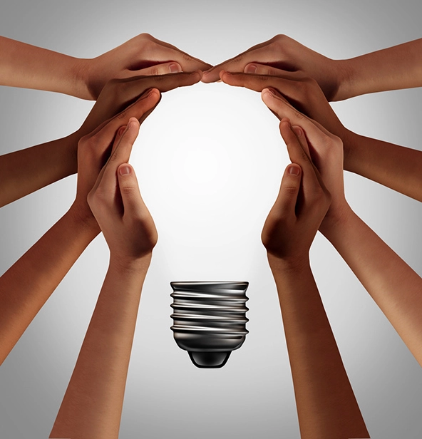Eight hands creating the shape of a lightbulb