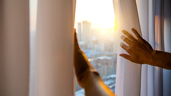 Hands opening curtain in the morning