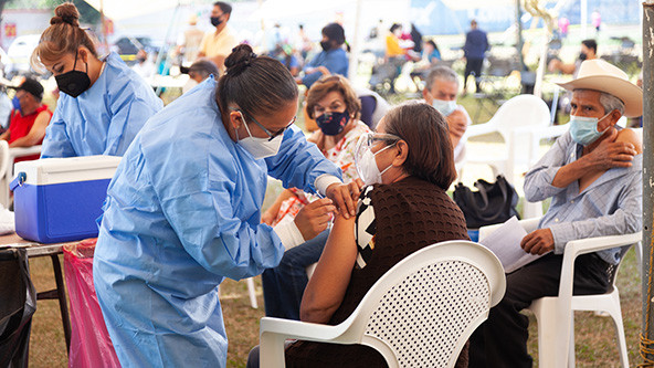 Public health personnel vaccinating seniors against COVID-19 at a pop-up vaccination center on a soccer field in Mexico