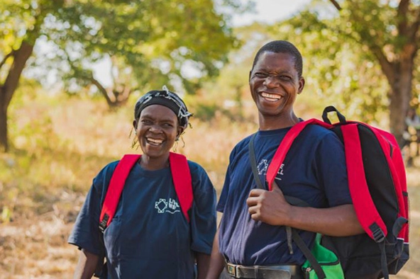 Two people wearing backpacks smiling at the camera.