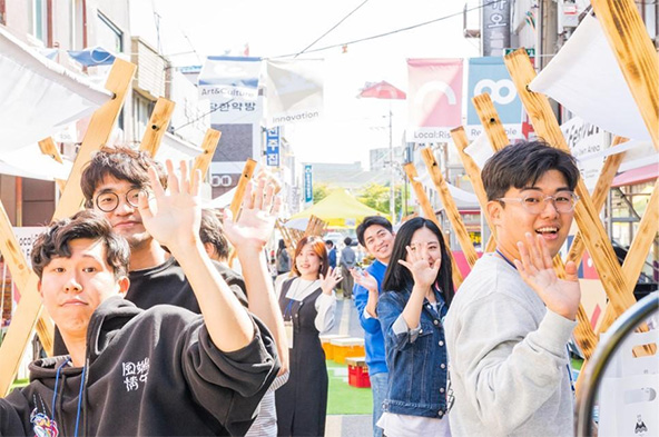 Young people in a street waving at camera
