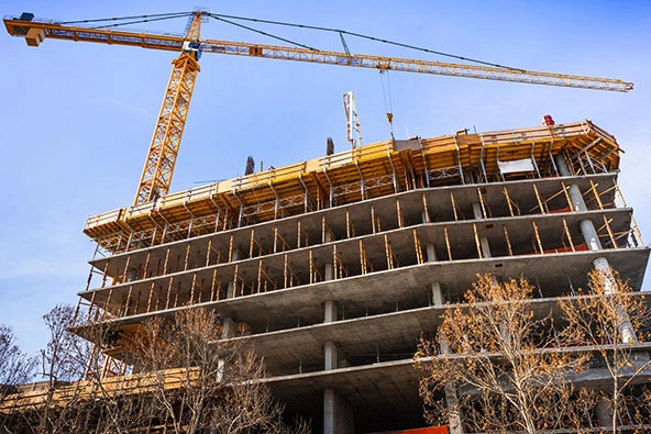 Multi-level concrete building under construction with tower crane