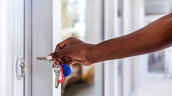 [close up of Black woman unlocking front door of business]
