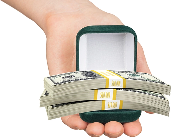 Hand holding green ring box filled with cash