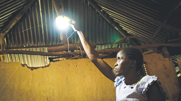 woman reaching up to turn on a lightbulb hanging from ceiling