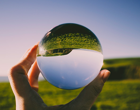 Hand holding a crystal photo ball that shows the horizon flipped upside down
