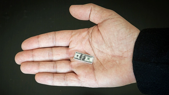 tiny $100 bill in the palm of a hand