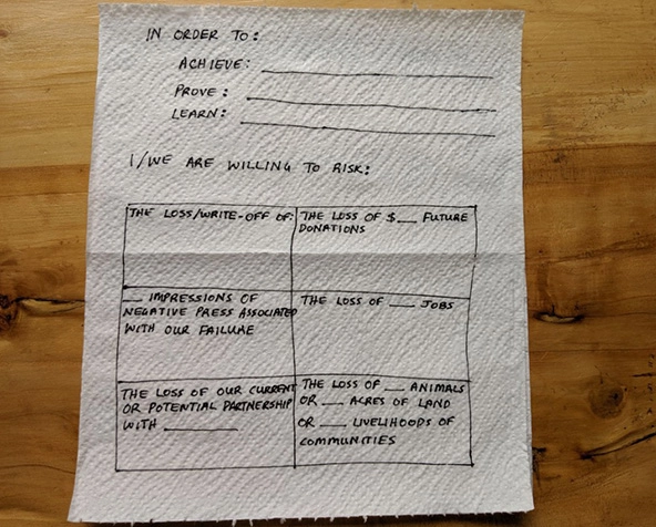 A napkin with the words: In order to achieve, prover, learn...I/we are willing to risk: the loss/write-off of X; the loss of x$ in donations; x impressions of negative press; the loss of x jobs; the loss of current or potential partnerships with x;