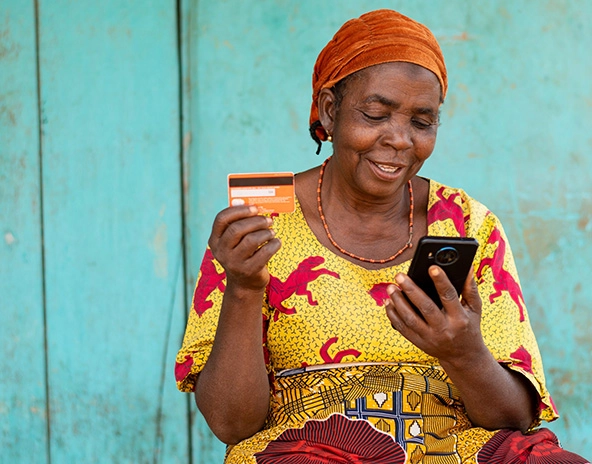 Elderly African woman holding her smartphone and credit card