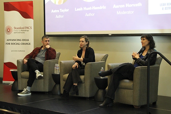 Three people sitting in chairs on a stage