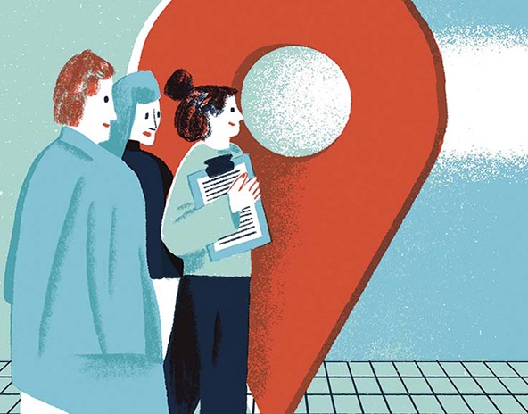 Three people standing next to a life-size drop pin on a map