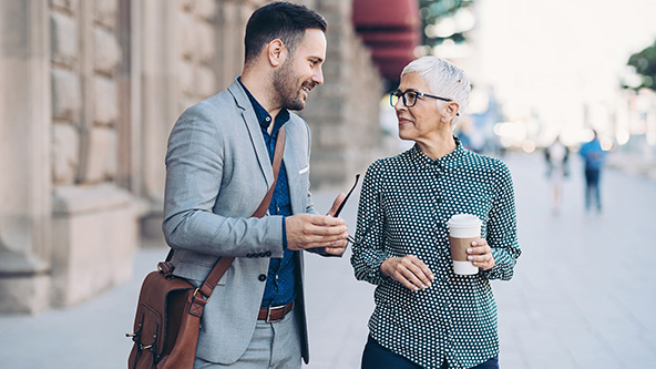 Two people in business attire walking and talking together
