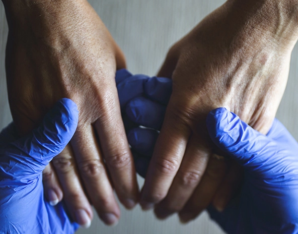 Hands wearing surgical gloves holding bare hands