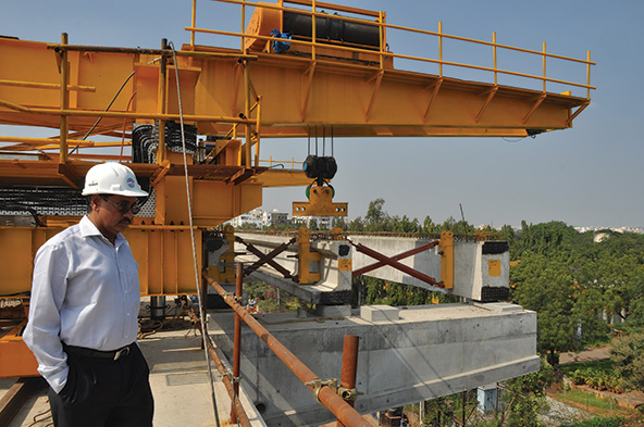 Man in hard hat overlooking construction of an elevated rail platform