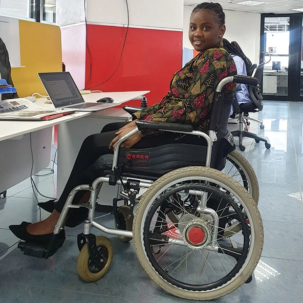 Kenyan woman in a wheelchair sits at a desk with a laptop