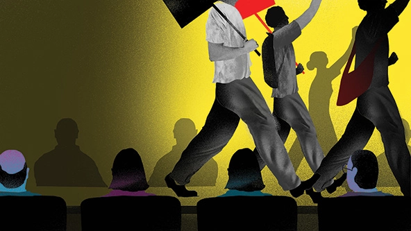 Protestors with signs walk by people in chairs