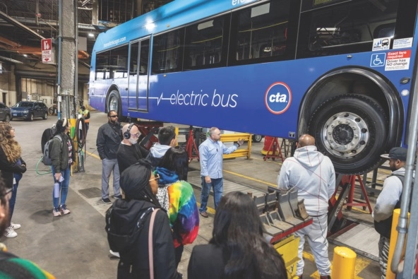 workers stand around electric bus in factory