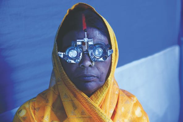 photo of woman in yellow robes wearing an eyesight checking mechanism that looks like a thick pair of industrial glasses