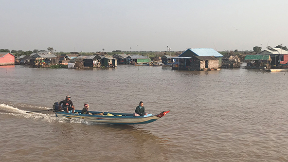 A fishing boat, with its net submerged, coasts through the Tonlé Sap