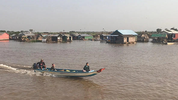 A fishing boat, with its net submerged, coasts through the Tonlé Sap