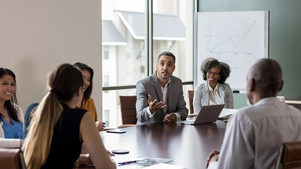 Man gestures as he talks with a group of people during a meeting