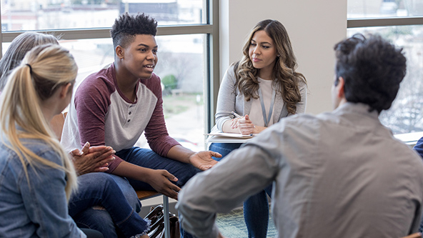As the therapy group members listen, a teen boy shares his experiences.