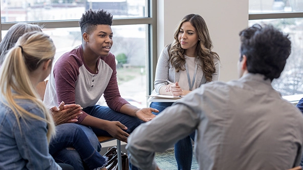 As the therapy group members listen, a teen boy shares his experiences.