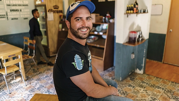 Man sitting in a restaurant facing camera.