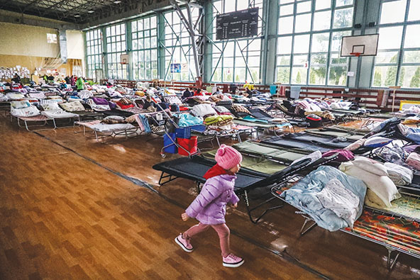 Refugees pictured among cots set up at a refugee shelter in Poland