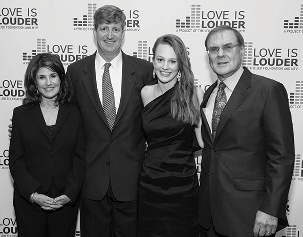 Four people standing in front of a step-and-repeat banner with the words 
