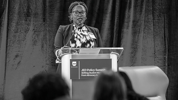 Black woman standing at a podium and speaking to a crowd