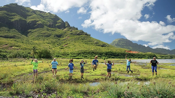 students outside in a grassy area next to a pond