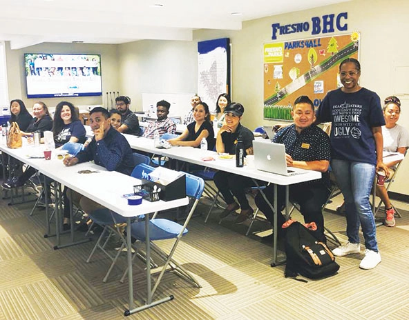 People sitting at long tables; facing the camera and smiling