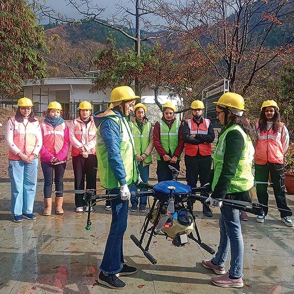 Two women in hardhats lifting a drone by its blades