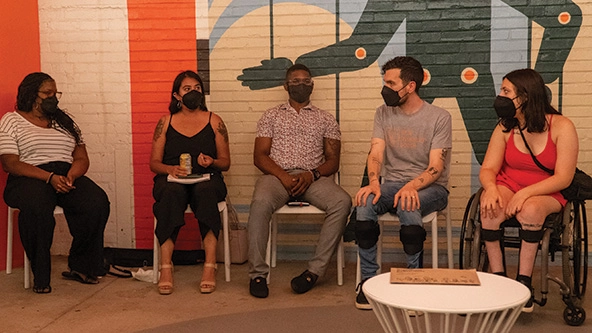 Five disabled community members sitting in chairs having a conversation