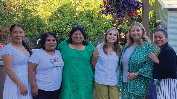 six women standing together, smiling for camera