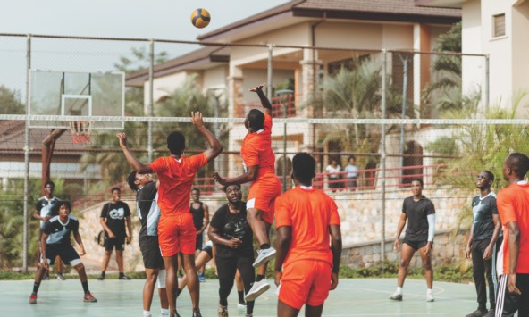 students playing volleyball outside in a university setting
