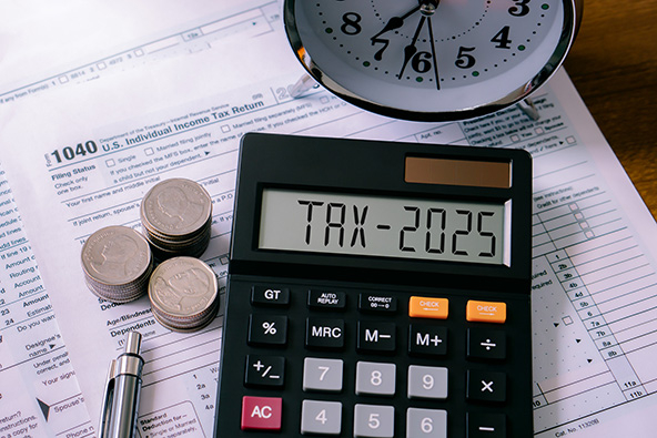 Photo of tax forms, calculator, stacks of coins, and alarm clock