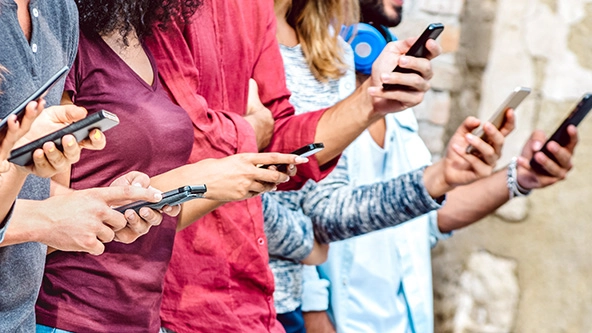 Cropped view of people standing in a row holding cell phones