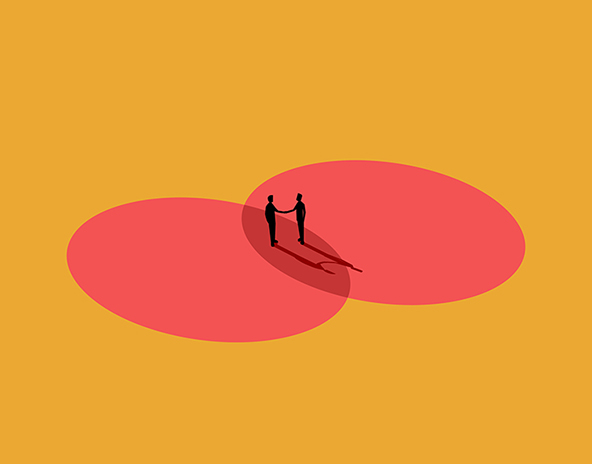 Two businessmen shake hands at the intersection of two circles