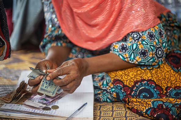 Woman in colorful African dress counting money on table