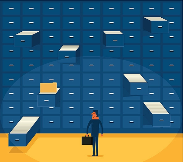 Person holding a briefcase standing in front of a wall of filing cabinets.