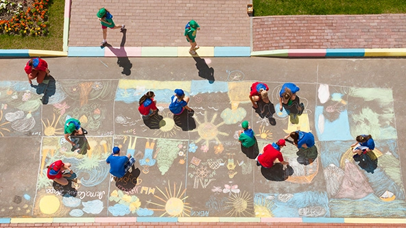overhead view of children making chalk drawings on the sidewalk