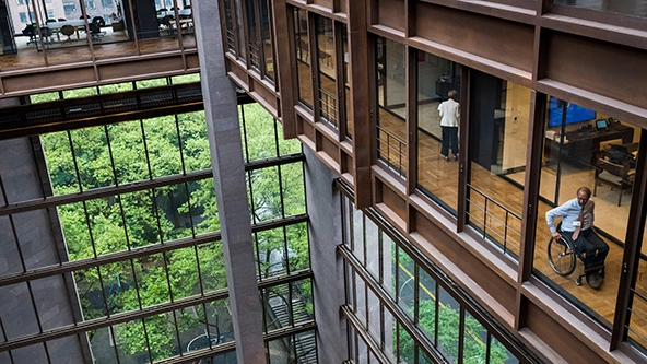 A man in a wheelchair moving down an interior hallway.