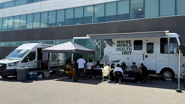 two mobile health vans and a tent set up outside a building