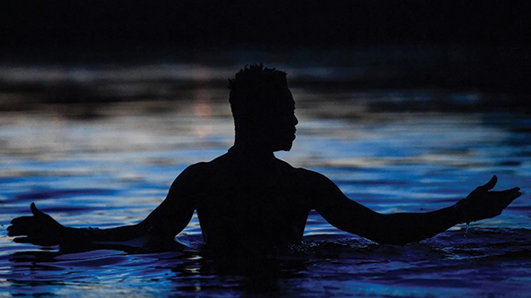 A person wading in water with their arms outstretched