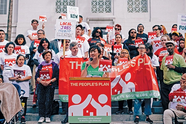 People rallying the steps of City Hall in Los Angeles, many holding hands that say 